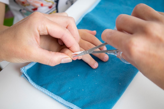 Children's manicure Female hands cut nails on children's hands with manicure scissors