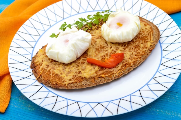 Children's menu hot sandwich of black rye bread with grated cheese and a poached egg