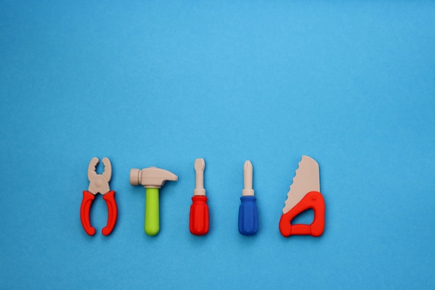 Children's mini versions of screwdrivers, saws, hammer and pliers on a blue.