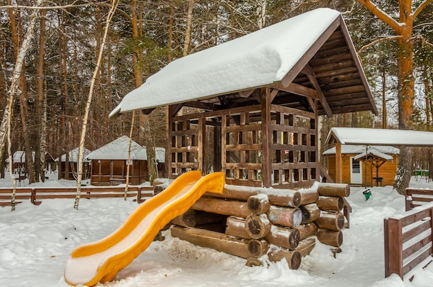 Children's slide made of wood in the park in winter.