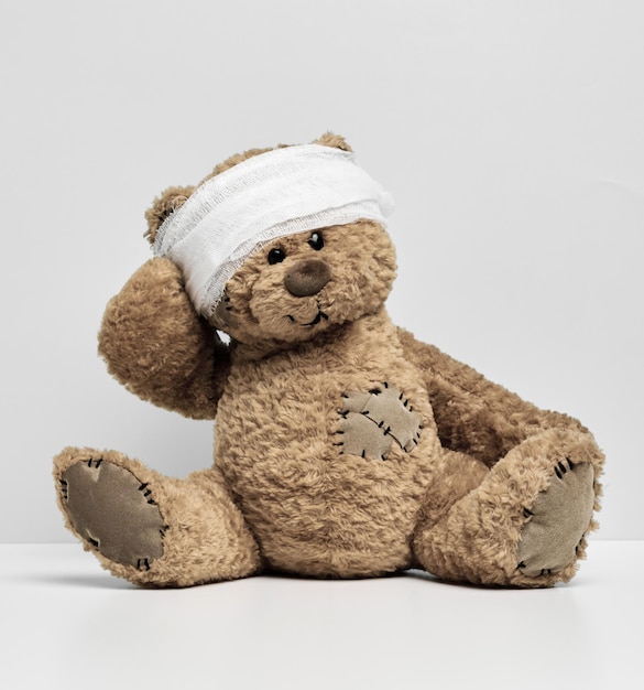 Children's toy teddy bear sits with a bandaged head Childhood trauma concept