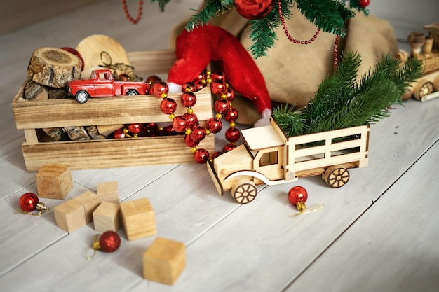 Children's toys and gifts on the floor under the Christmas tree Postcard with tilke rustic Wooden truck santa hat and wooden cupcakes