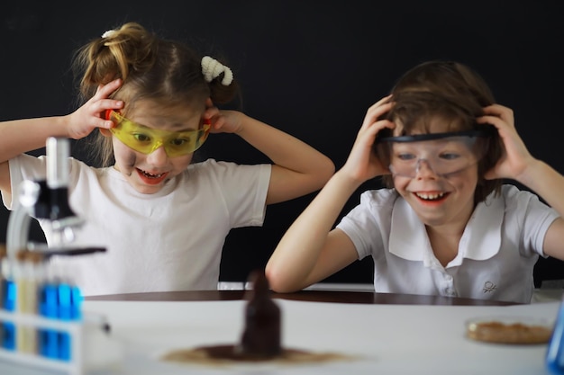 Children scientists Schoolchildren in the laboratory conduct experiments Boy and girl experiments with a microscope