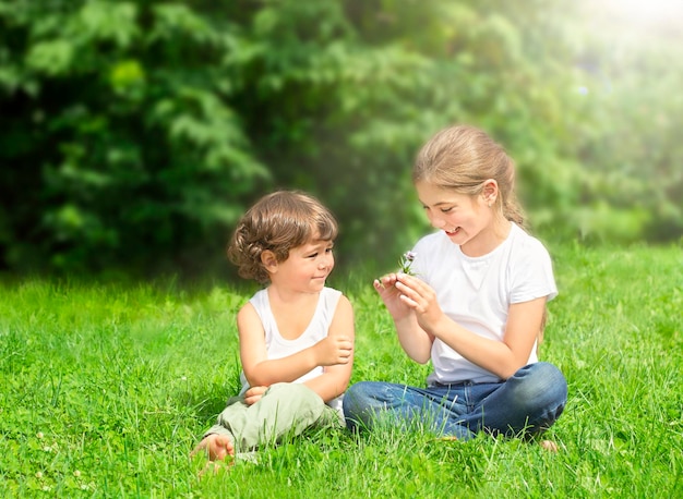 children sit on the grass outdoors and smile