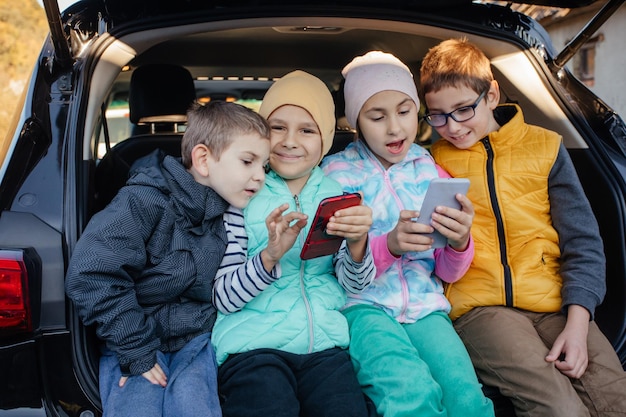 Children sitting on the car truck with smartphones