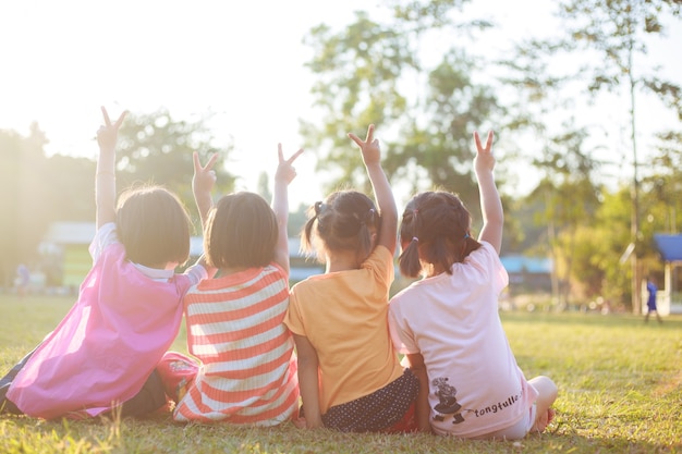 Children sitting on green grass in the park.