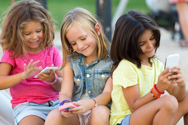 Children sitting with smartphones in street