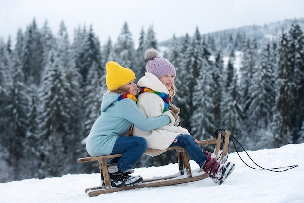 Children on sleigh kids boy and girl plays outside in the snow winter holiday and christmas