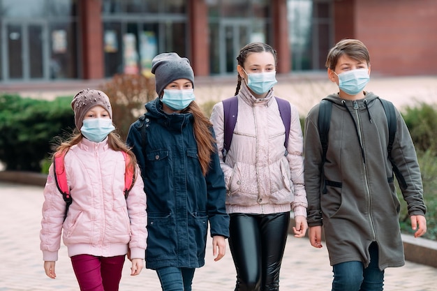 Children students in medical masks leave the school.