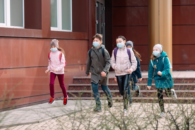 Children students in medical masks leave the school.