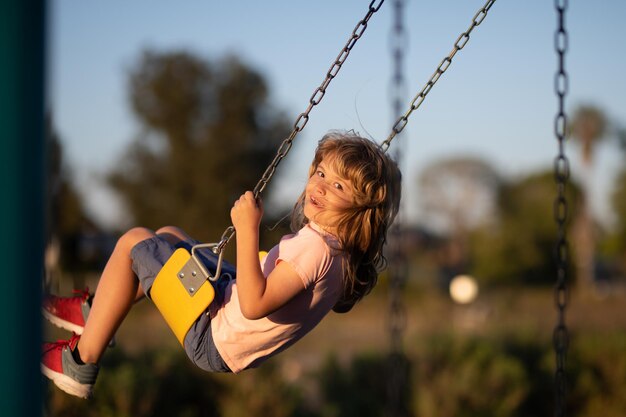 Children swinging on the playground cute little kid boy funny while playing on the playground summer