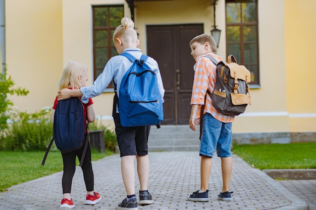 children walking to school with backpacks on sunny day. Begining of academic year. Boys by school do