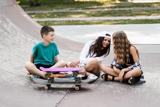 Children with skateboard and penny boards communicate and discuss on the sports playground Children friendship concept Children smile and laugh and have fun together