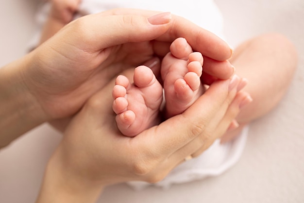 Children39s foot in the hands of mother father parents Feet of a tiny newborn close up Little baby legs Mom and her child Happy family concept Beautiful concept image of motherhood stock photo