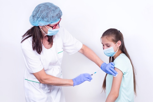 Childrens doctor or nurse giving shot vaccine to patients shoulder  young girl teenager vaccination