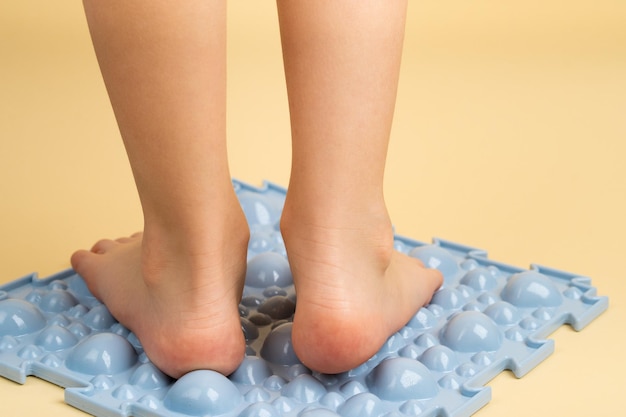 Childrens feet on a blue orthopedic rug on a beige background treatment and prevention of flat feet