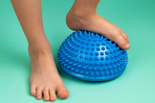 Childrens feet with a blue balancer on a light green background treatment and prevention of flat