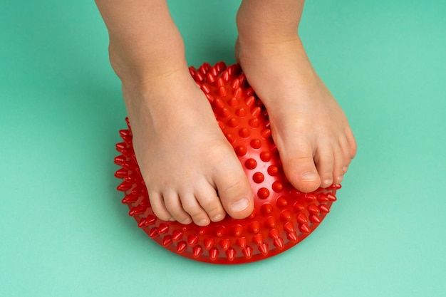 Childrens feet with a red balancer on a light green background treatment and prevention of flat feet