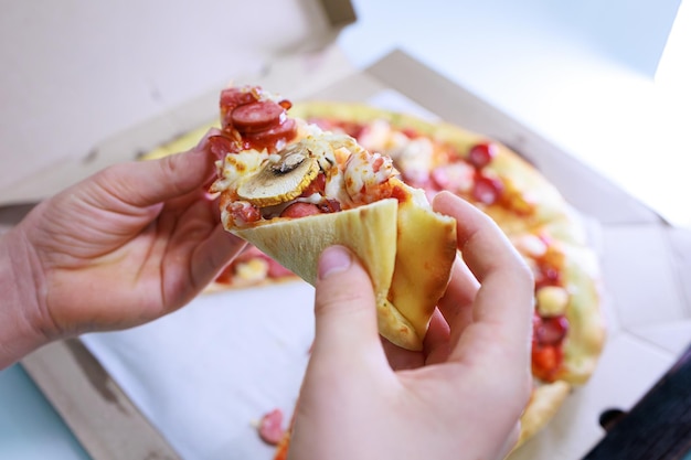 The childrens hands hold a slice of pizza in front of them Sausage and cheese pizza