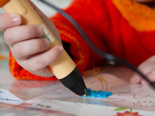 Childrens hands make a craft using a 3D printing pen A girl draws with a 3D pen