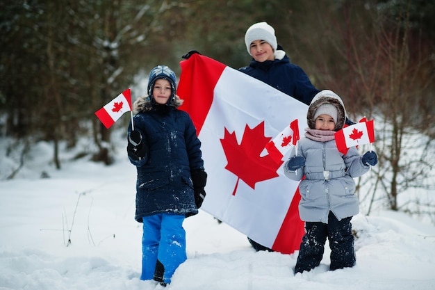 Childrens holding flag of Canada on winter landscape.