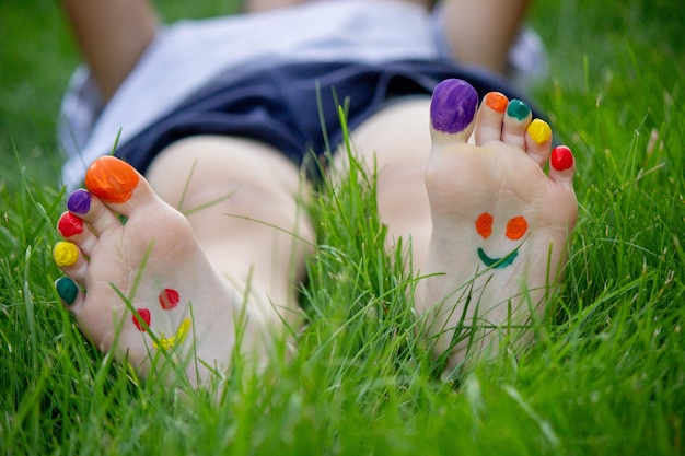 Childrens legs with a pattern made of paints are smiling on the green grass