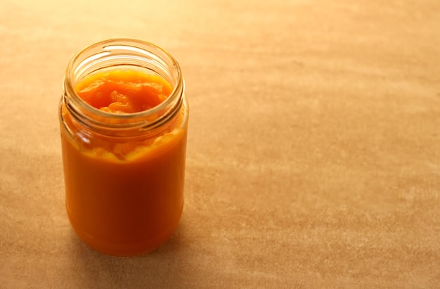 Childrens pumpkin puree in a glass jar on a beige background