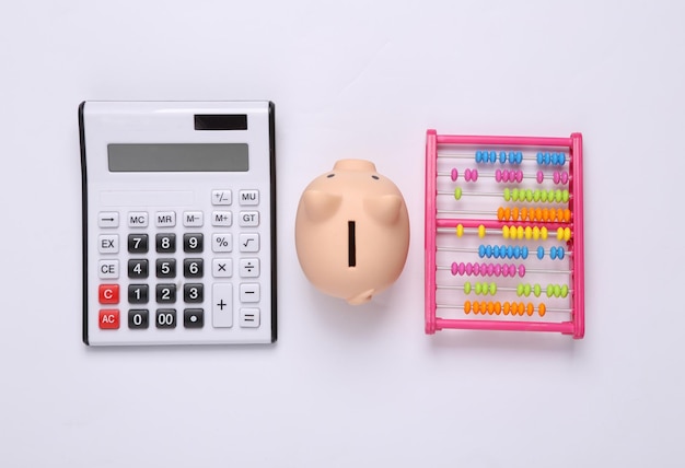 Childrens toy abacus with piggy bank and calculator on white background Economic concept