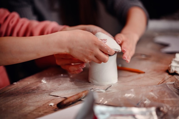 Photo a childs hands carefully construct a clay house with the focused guidance of a parent symbolizing the foundational joy of building and learning together