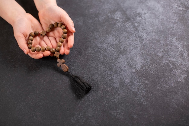 Childs hands holding the wooden cross and beads th in the shape of a heart