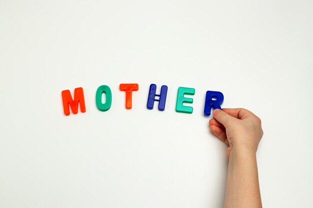 The childs hands and the word mother made of multicolored letters