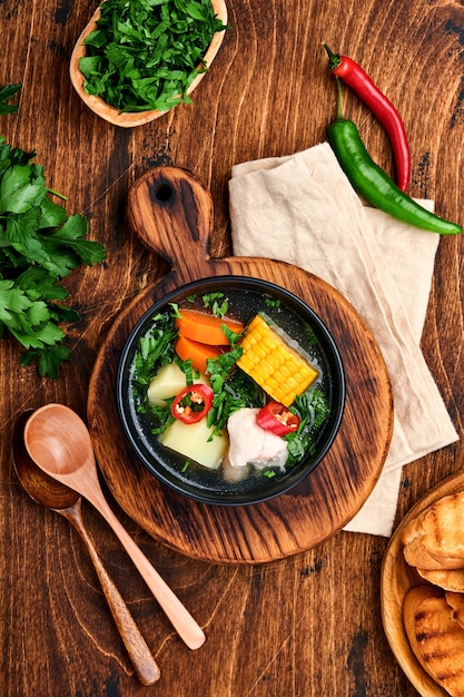 Chilean meat soup with pampkin, corn, fresh coriander and potatoes on old wooden table background. Cazuela. Latinamerican food.