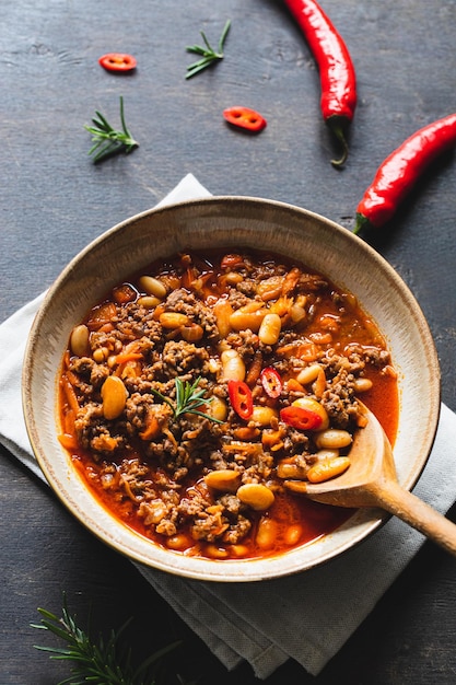 Chili Con Carne in bowl on dark background Mexican cuisine chili con carne minced meat and vegetables stew in tomato sauce Top view