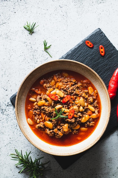 Chili Con Carne in bowl on light grey stone or concrete background Mexican cuisine chili con carne minced meat and vegetables stew in tomato sauce Top view