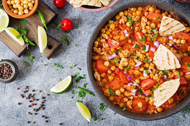 Chili con carne of turkey  with chickpeas served with nachos.  Chili with meat, nachos, lime, hot pepper. Mexican / Texas traditional food. Top view