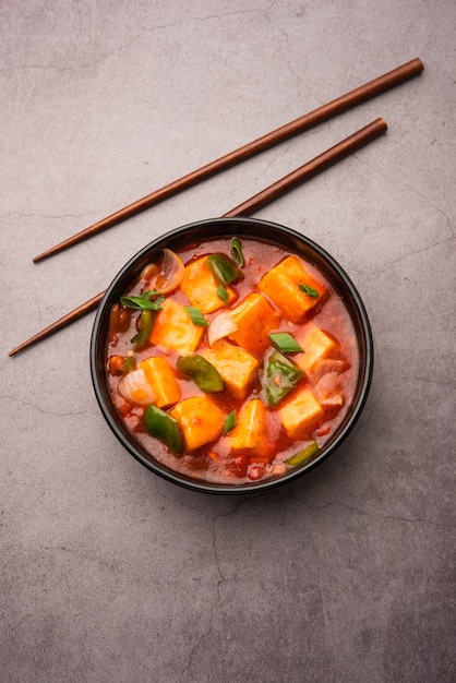 Chilli paneer or Spicy cottage cheese, served in bowl with capsicum and onion, favourite indian starter menu