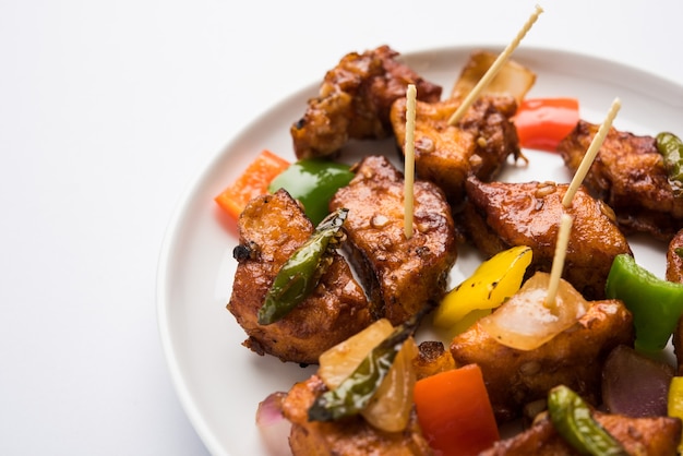 Chilli paneer or Spicy cottage cheese, served in white Dish with capsicum and onion, favourite indian starter menu, selective focus