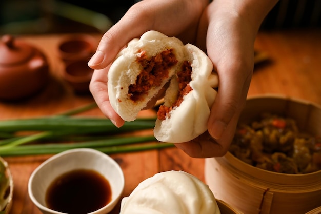 Chinese dim sum cuisine Female hands holding a steamed pork bun