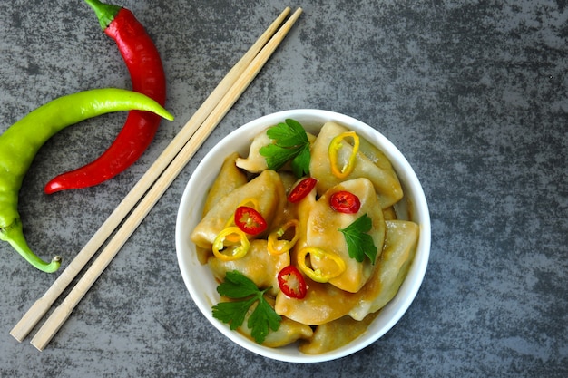 Chinese dumplings in white bowl with chili pepper