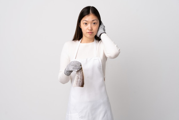 Chinese fishmonger wearing an apron and holding a raw fish isolated