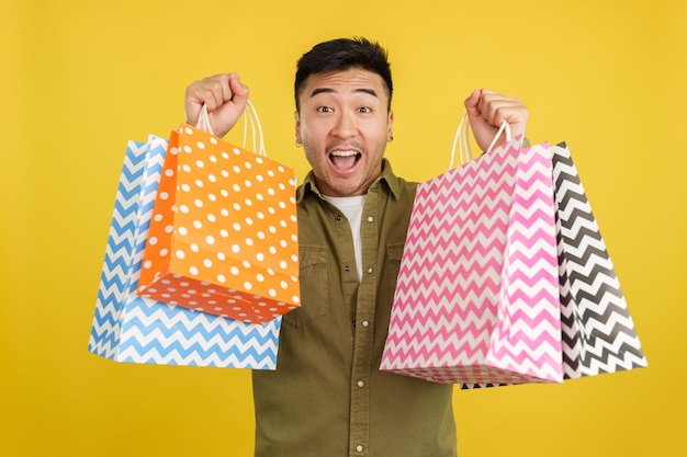 Chinese man raising many shopping bags while smiling