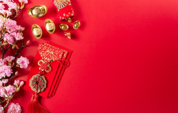 Chinese new year decorations made from red packet, orange and gold ingots or golden lump on a red background. Chinese characters FU in the article refer to fortune good luck, wealth, money flow.