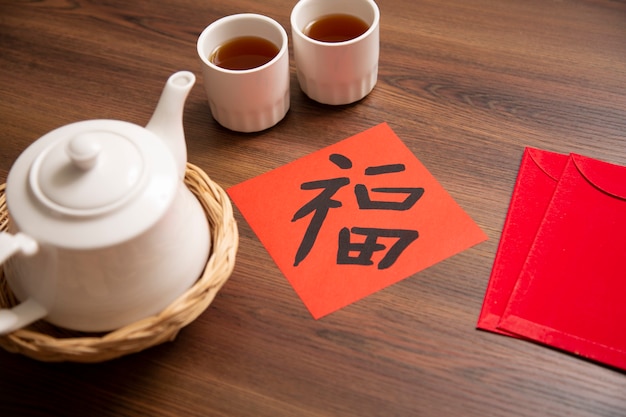 Chinese New Year and Lunar New Year celebrations with gold bar giving red envelope and hot tea. The Chinese Word means : Blessing, happiness and lucky