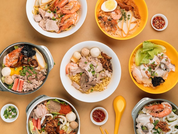 Chinese seafood table with Tom Yum Xiao Wan Sliced Fish Porridge Bee Hoon Black Soya Sauce in a bowl with soup chili sauce spring onion top view on wooden table chinese seafood noodle table