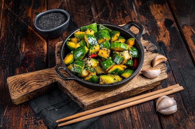 Chinese Smashed Cucumber salad pai huang gua in a skillet Wooden background Top view