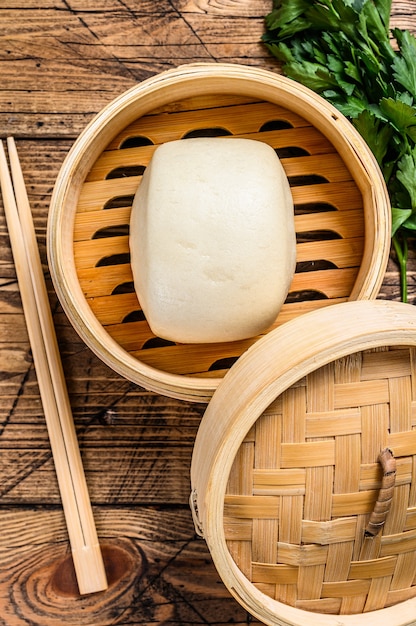 Chinese Steamed Buns in traditional bamboo steamer. Wooden background. Top view.