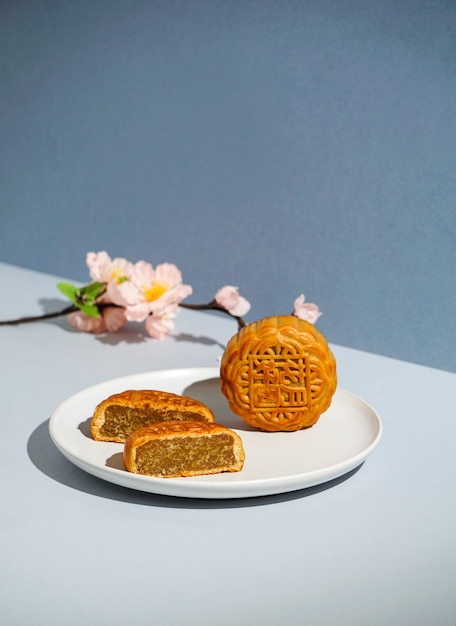 Photo chinese traditional pastry moon cake, mooncake, the chinese character on the cake translation in english is"lotus paste", mid-autumn festival, harsh sun light, blue background, modern still life