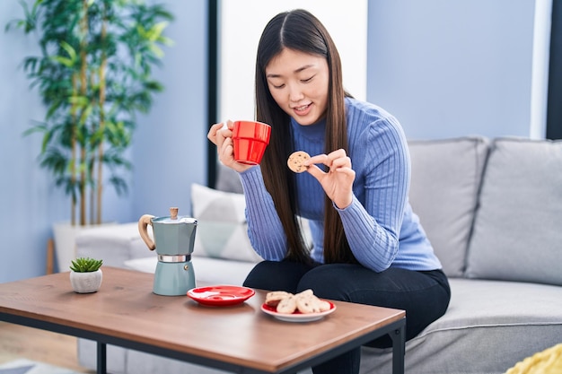 Chinese woman having breakfast sitting on sofa at home