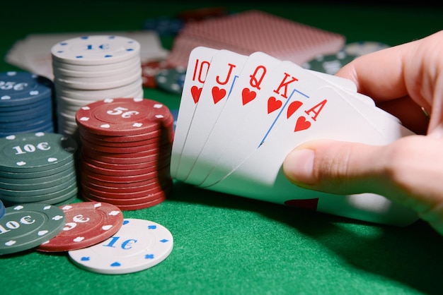 Chips and cards for poker in hand on green table