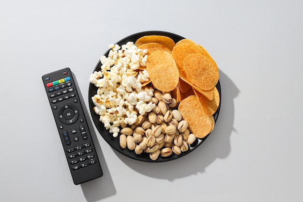 Chips and popcorn in a bowl with a remote control